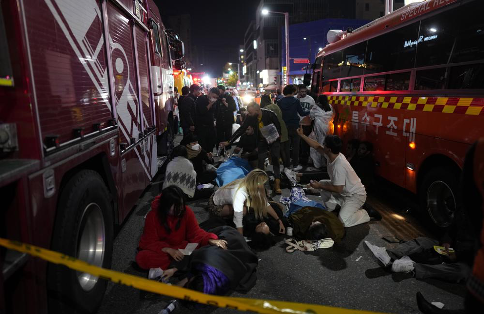 Injured people are helped at the street near the scene in Seoul, South Korea, early Sunday, Oct. 30, 2022. South Korean officials said around 50 people were in cardiac arrest and a number feared dead after being crushed by a large crowd pushing forward on a narrow street during Halloween festivities in the capital Seoul. (AP Photo/Lee Jin-man)