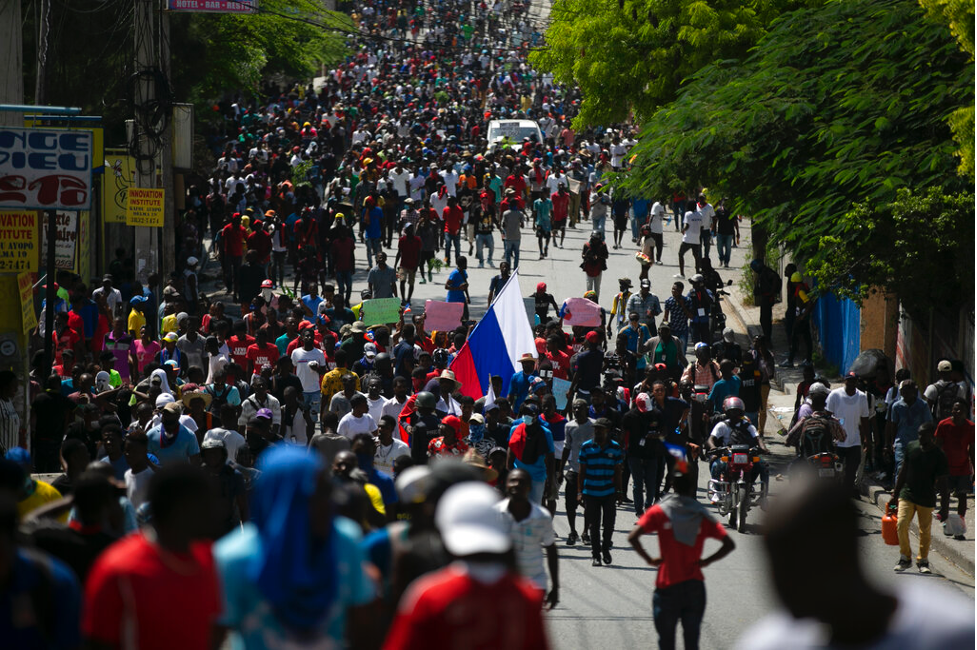 Haitians protest to reject an international military force and to demand the resignation of unelected Prime Minister Ariel Henry in Port-au-Prince, Haiti on Oct. 17, 2022. One protester holds a Russian flag, highlighting the anti-American and anti-Western nature of popular Haitian sentiment. (AP Photo/Odelyn Joseph)
